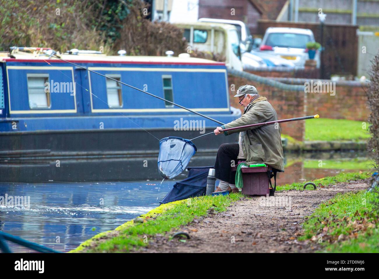 Stourbridge, Regno Unito. 15 dicembre 2023. Meteo britannico: È una mattinata fredda e noiosa nelle Midlands, ma non impedisce alle persone di uscire e godersi il passatempo preferito. Questo signore mette a rete un pesce pescato sul canale durante una tranquilla mattinata di pesca, lontano dal trambusto dello shopping natalizio. Credito: Lee Hudson/Alamy Live News Foto Stock