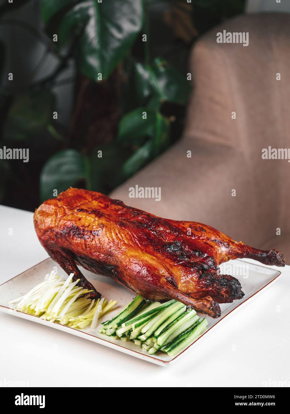 Anatra arrostita al forno - anatra intera al forno con cetriolo verde fresco e cipolla. Anatra di Pechino intera sul tavolo del ristorante. L'anatra di Pechino è un piatto tradizionale cinese Foto Stock
