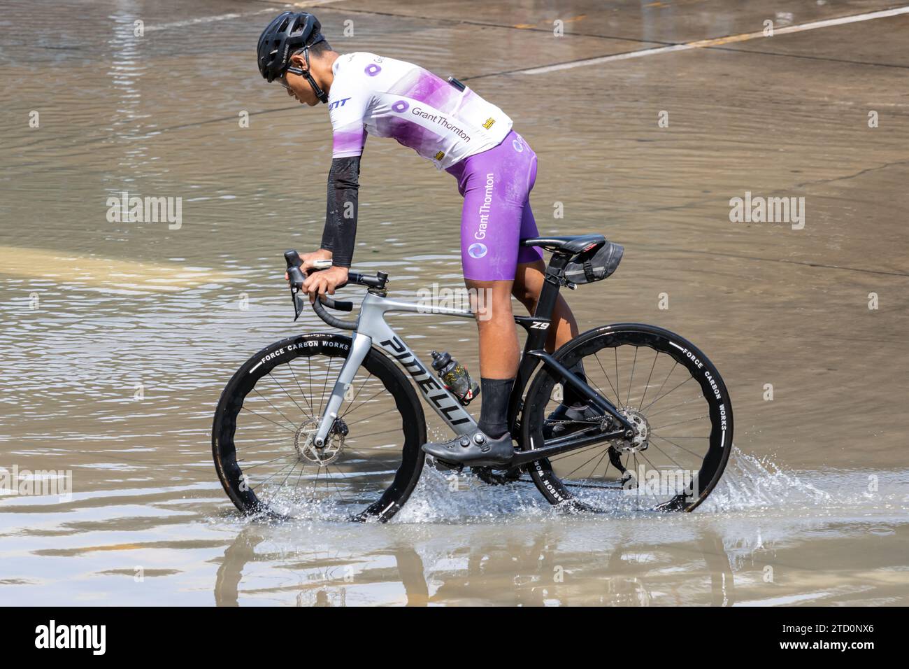 SAMUT PRAKAN, TAILANDIA, 18 novembre 2023, Un ciclista su strada pedala attraverso una strada allagata Foto Stock