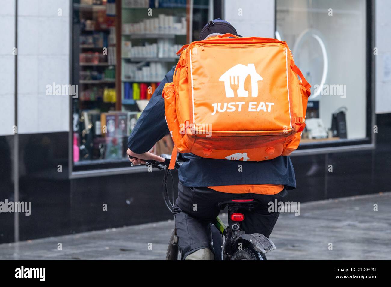 Basta mangiare un pilota su una bicicletta che fa una consegna di cibo a Cork, in Irlanda. Foto Stock