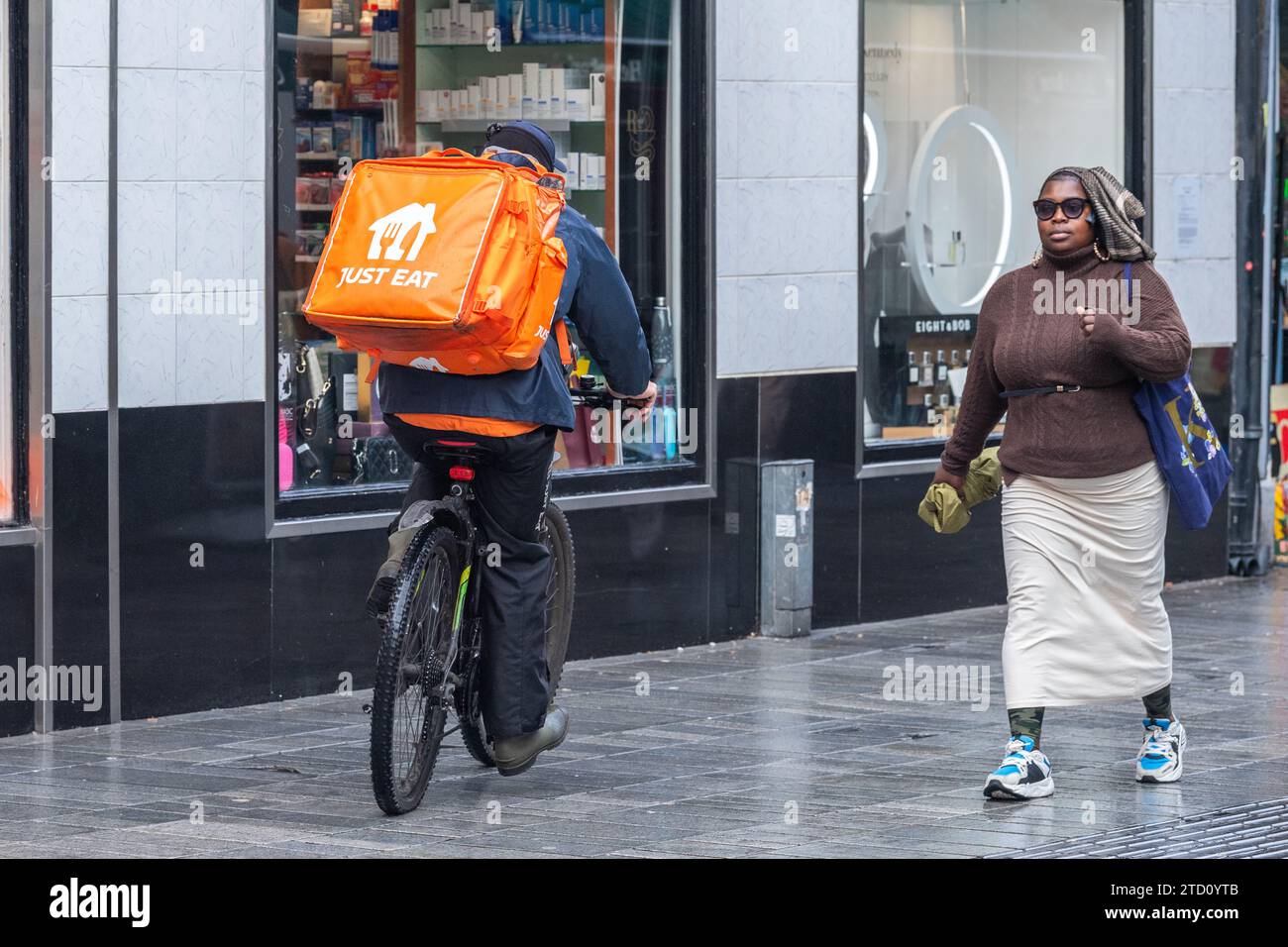 Basta mangiare un pilota su una bicicletta che fa una consegna di cibo a Cork, in Irlanda. Foto Stock