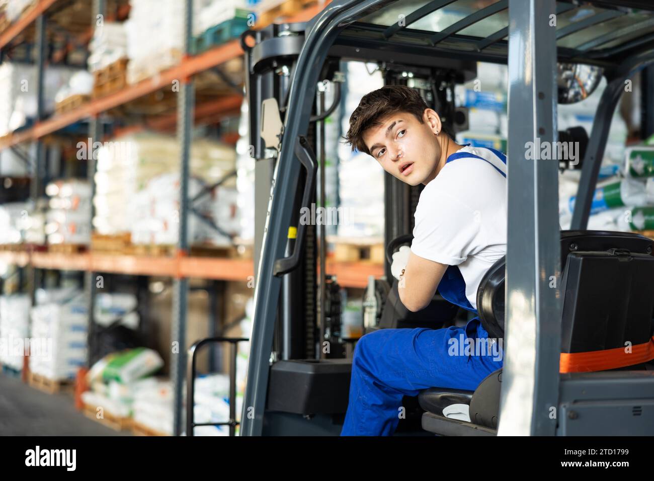 Guy lavora su un caricatore per carrelli elevatori a forche nei materiali di riparazione del magazzino per l'area delle scaffalature edili. Foto Stock