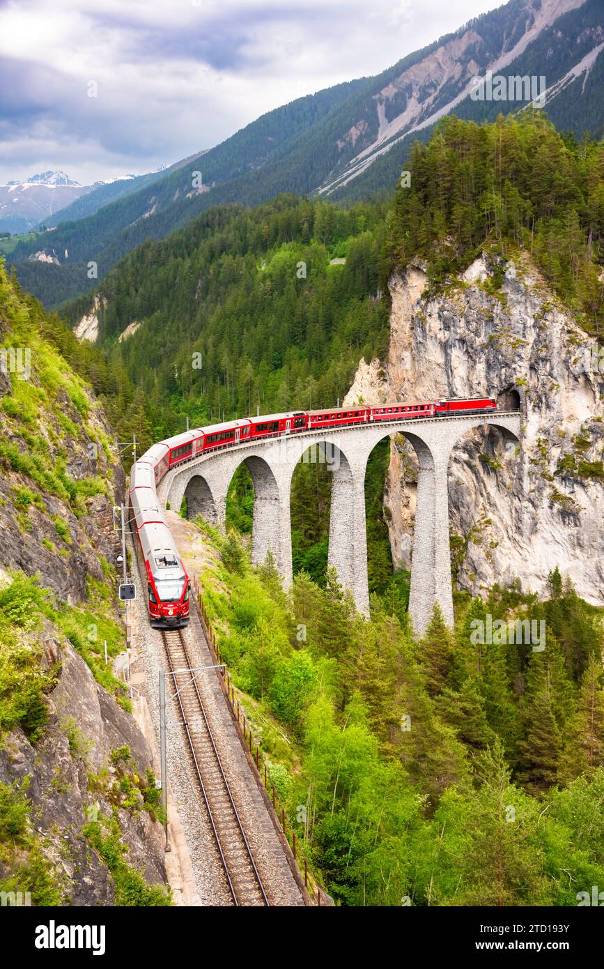 Treno rosso svizzero sul viadotto in montagna per un giro panoramico Foto Stock