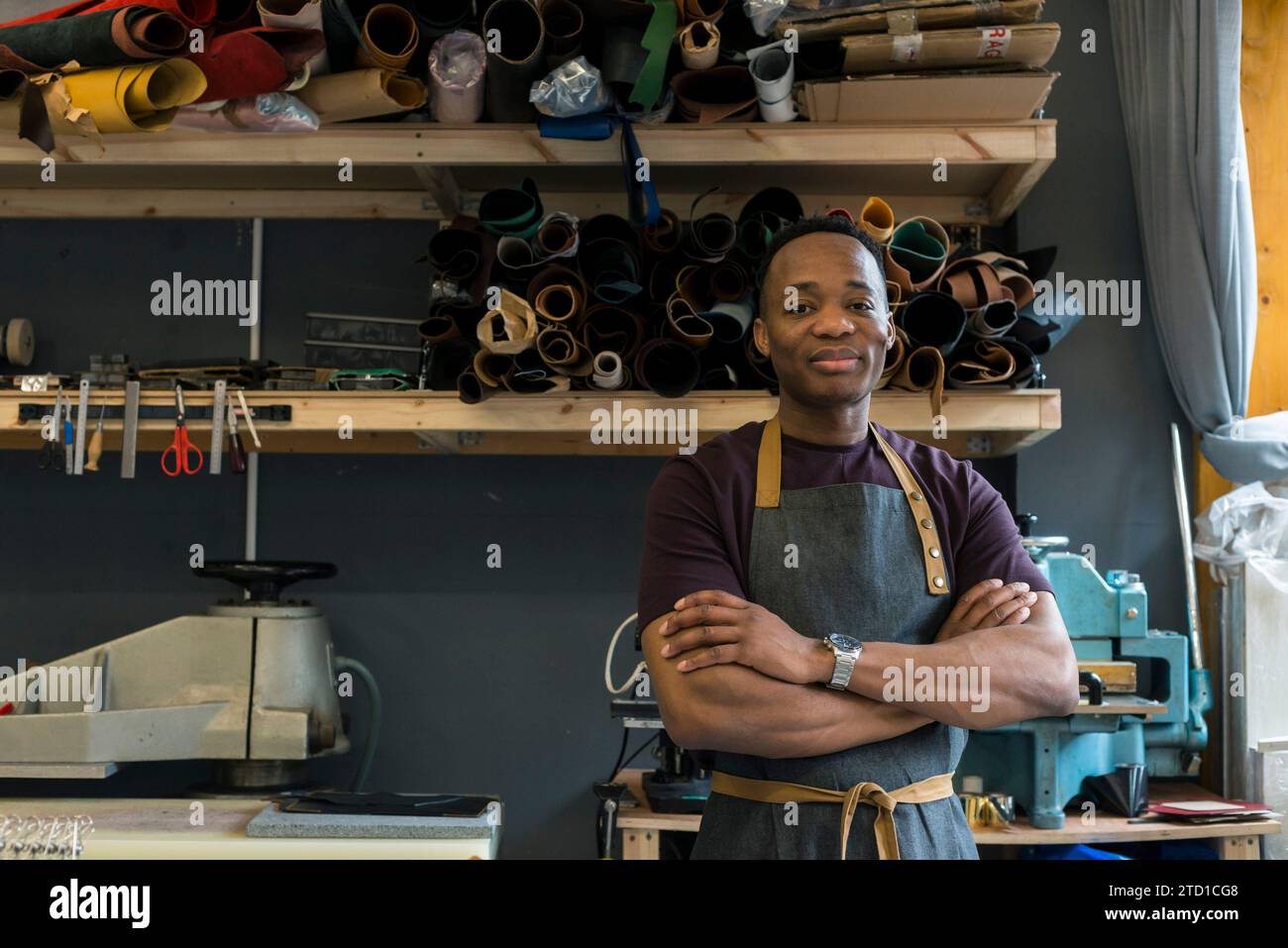 Un giovane si trova nella sua bottega di pelletteria dove disegna e realizza articoli di moda come borse, portafogli e cinture. Foto Stock