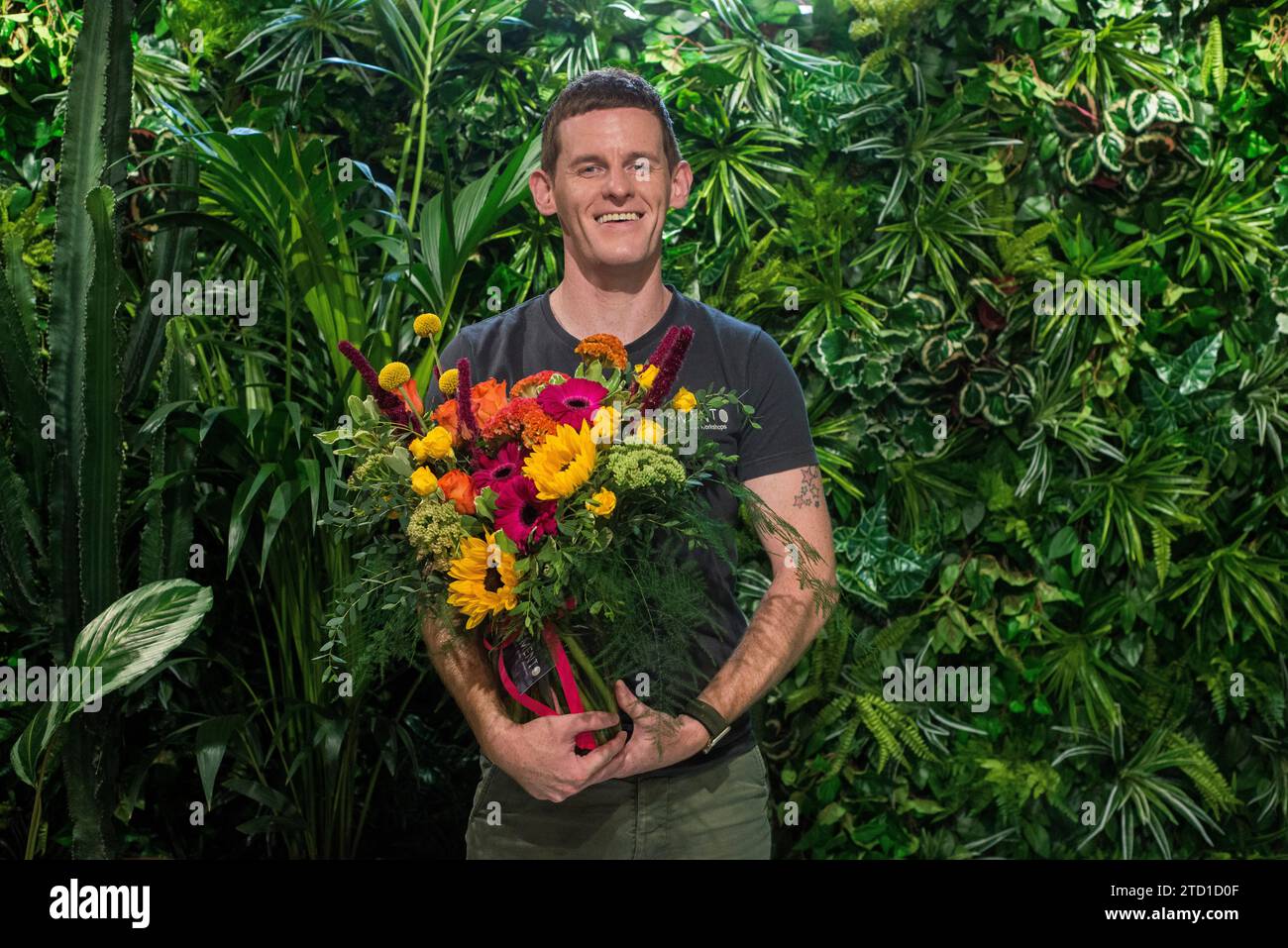 Una piccola azienda proprietaria di un fioraio si erge con un bouquet di fiori. Foto Stock