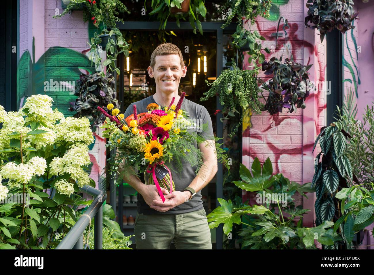 Una piccola azienda proprietaria di un fioraio si erge con un bouquet di fiori. Foto Stock