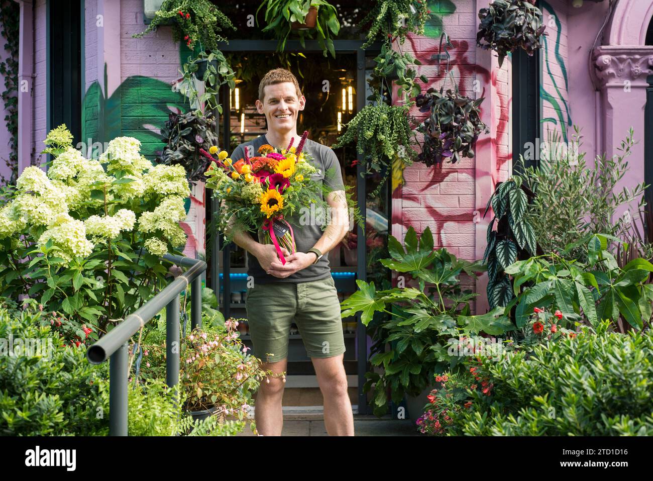 Una piccola azienda proprietaria di un fioraio si erge con un bouquet di fiori. Foto Stock