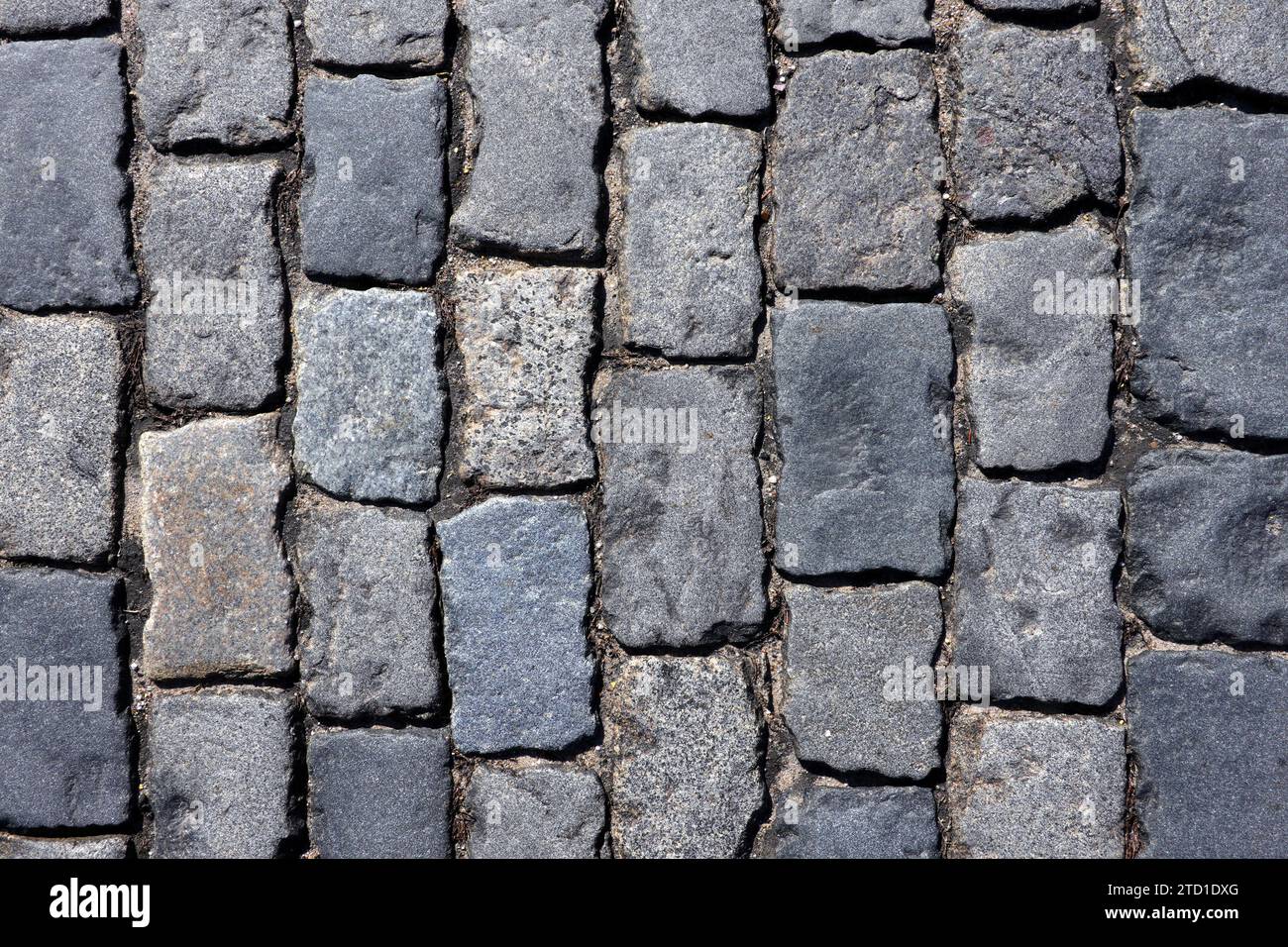 Pavimentazione in ciottoli grigio scuro con vecchie pietre lisce per una vista ravvicinata sullo sfondo Foto Stock