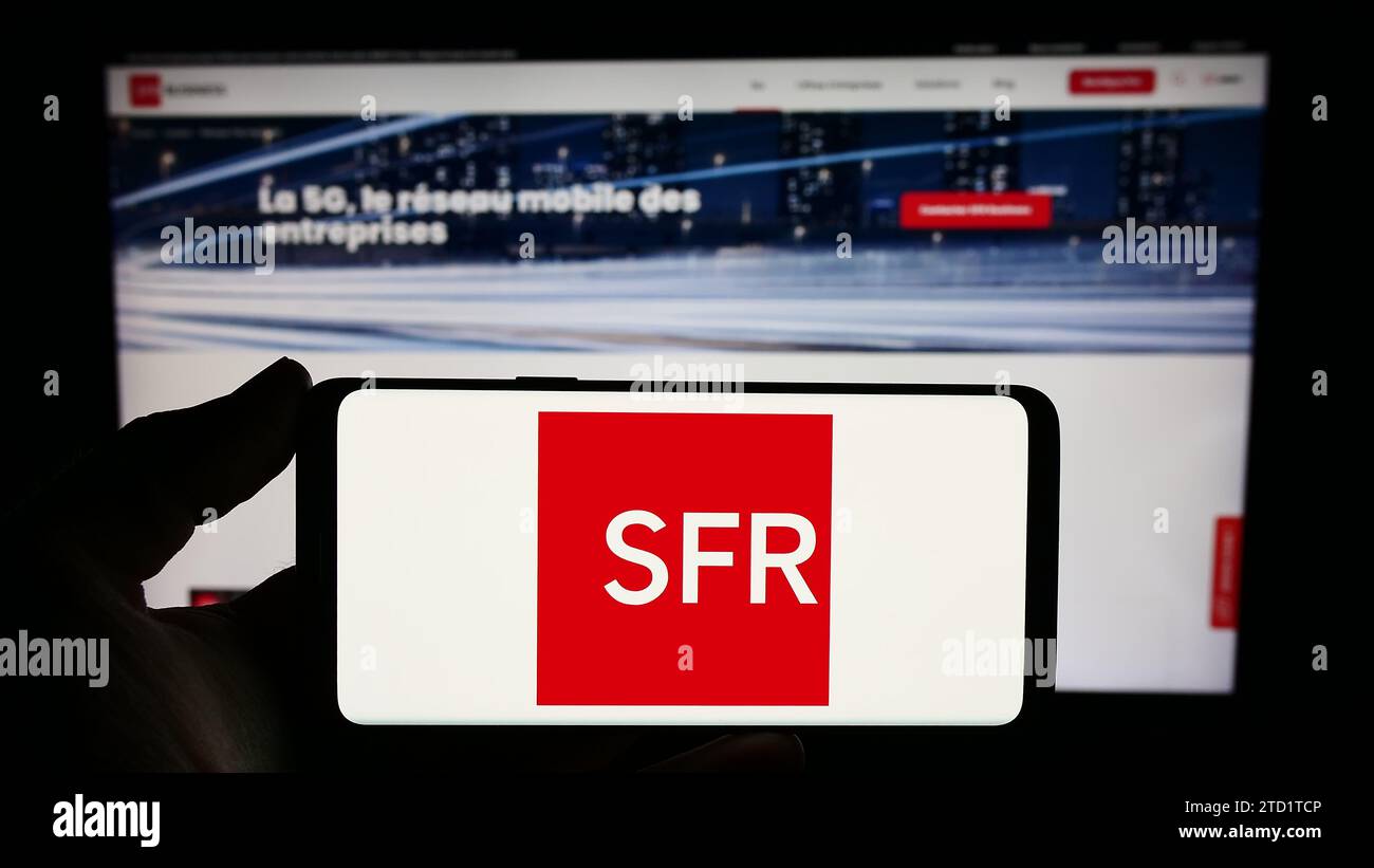 Persona che possiede uno smartphone con il logo della società francese Société Francaise du Radiotéléphone (SFR) davanti al sito web. Concentrarsi sul display del telefono. Foto Stock