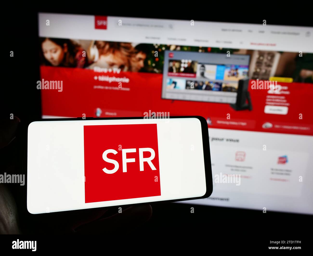 Persona che possiede il cellulare con il logo della società francese Société Francaise du Radiotéléphone (SFR) davanti alla pagina web. Concentrarsi sul display del telefono. Foto Stock