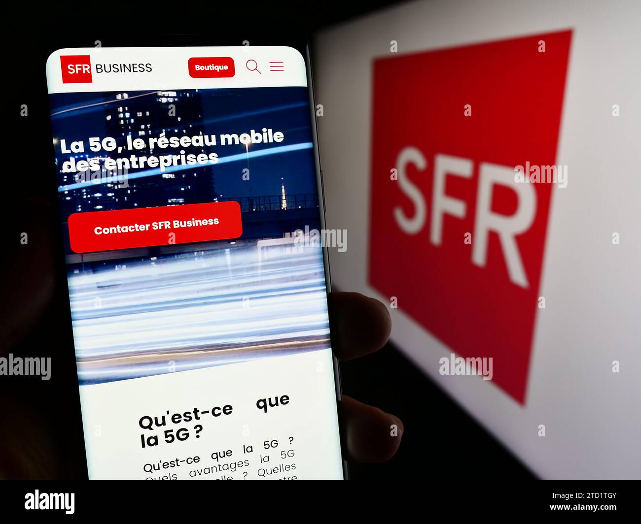 Persona in possesso di cellulare con pagina web della società francese Société Francaise du Radiotéléphone (SFR) con logo. Concentrarsi sul centro del display del telefono. Foto Stock