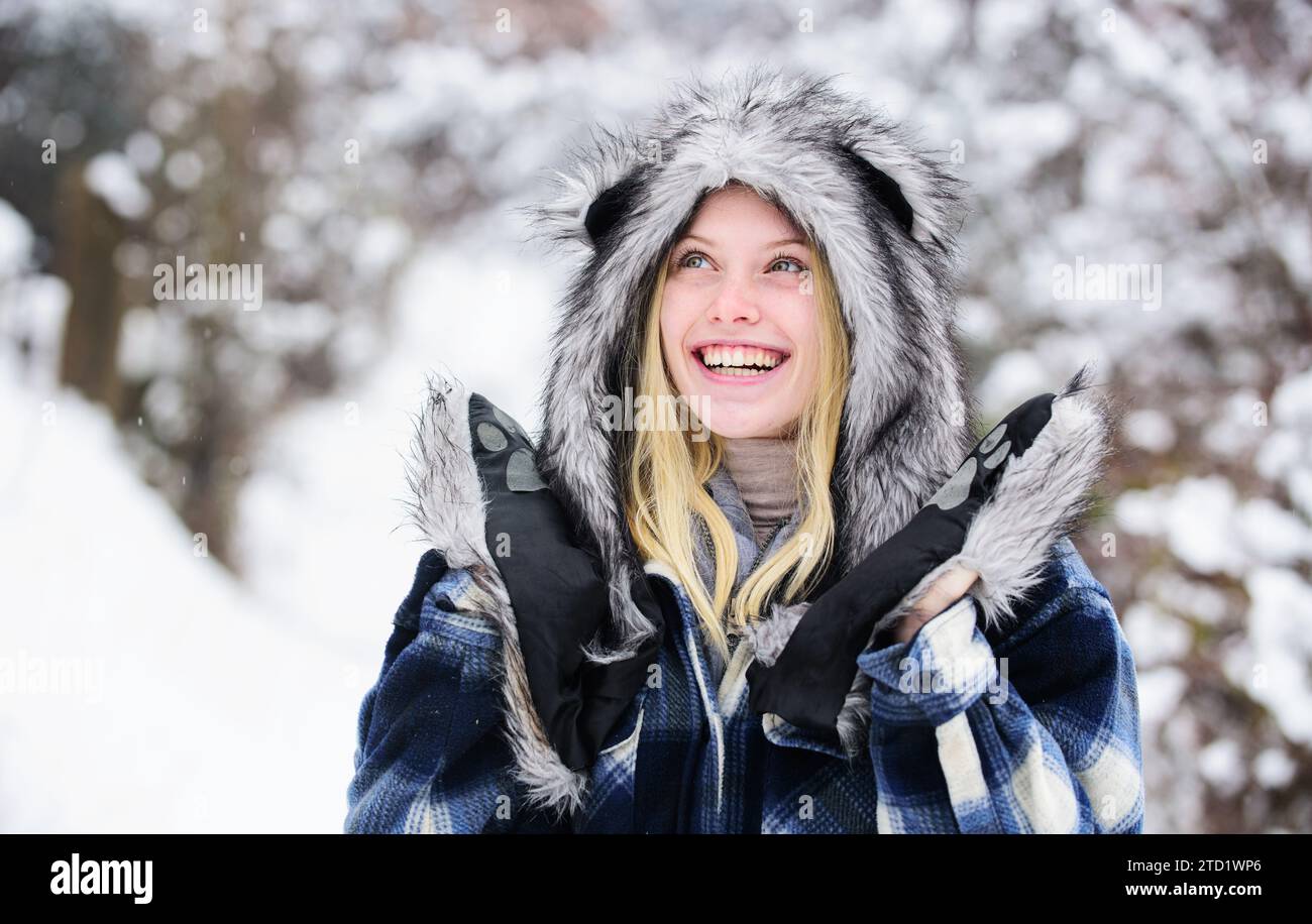 Donna felice che si gode una giornata invernale innevata. Ragazza natalizia con cappotto a quadri, cappello in pelliccia e guanti. Ragazza alla moda nella stagione invernale. Bella donna in caldo Foto Stock