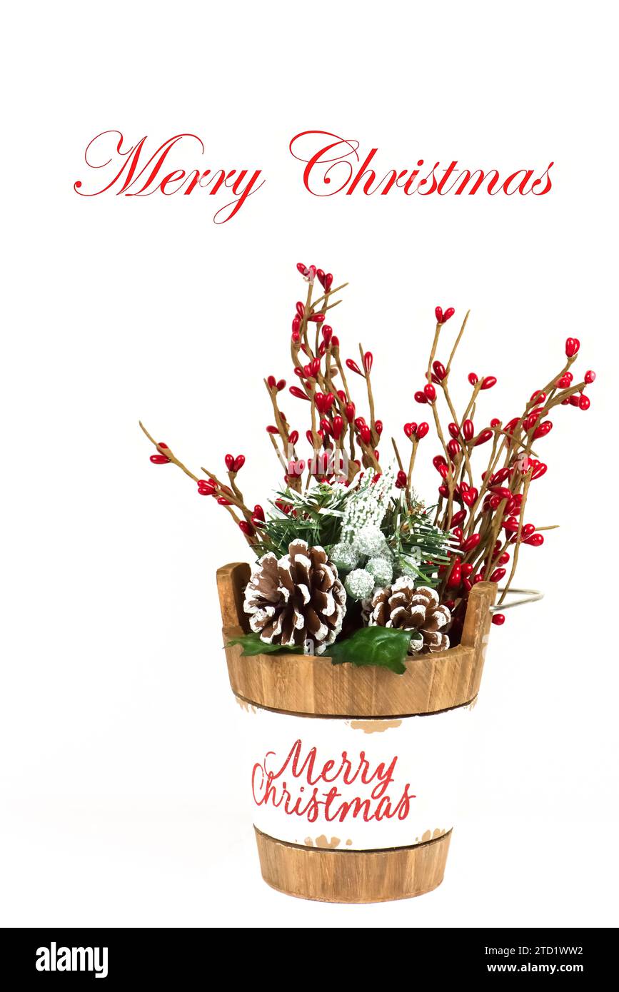 Biglietto d'auguri di buon Natale, sfondo, con secchiello in legno di buon Natale, pieno di bacche rosse e coni di pino innevato. Foto Stock