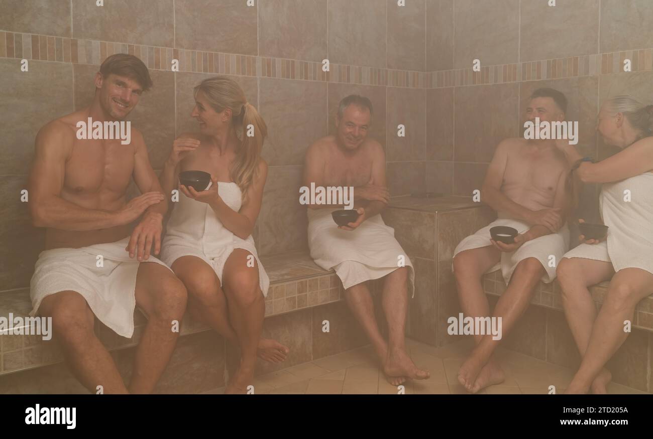 Gruppo di persone in un bagno turco, che si strofinano con il sale, chiacchierano e sorridono in un hotel benessere con centro benessere Foto Stock