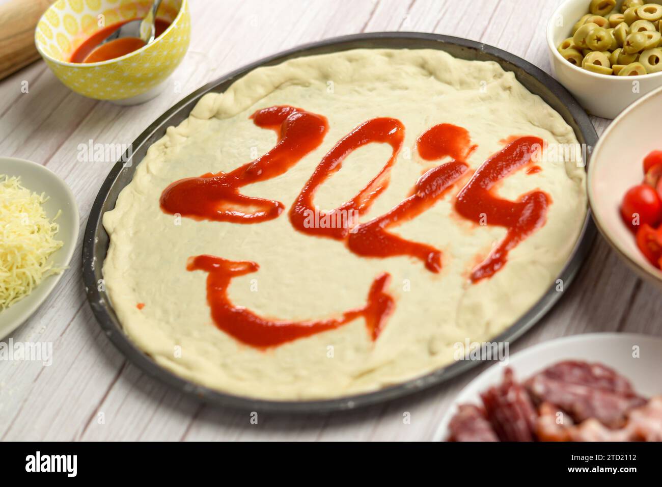 2024 contrassegnato con salsa di pomodoro su una pizza appena sfornata, accogliendo il nuovo anno con una delizia salata Foto Stock