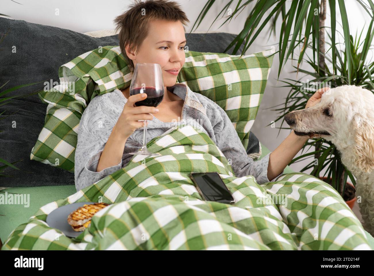 Una donna ama il suo tempo libero a letto con il suo grande barboncino. Il legame unico di un cane e del suo proprietario Foto Stock