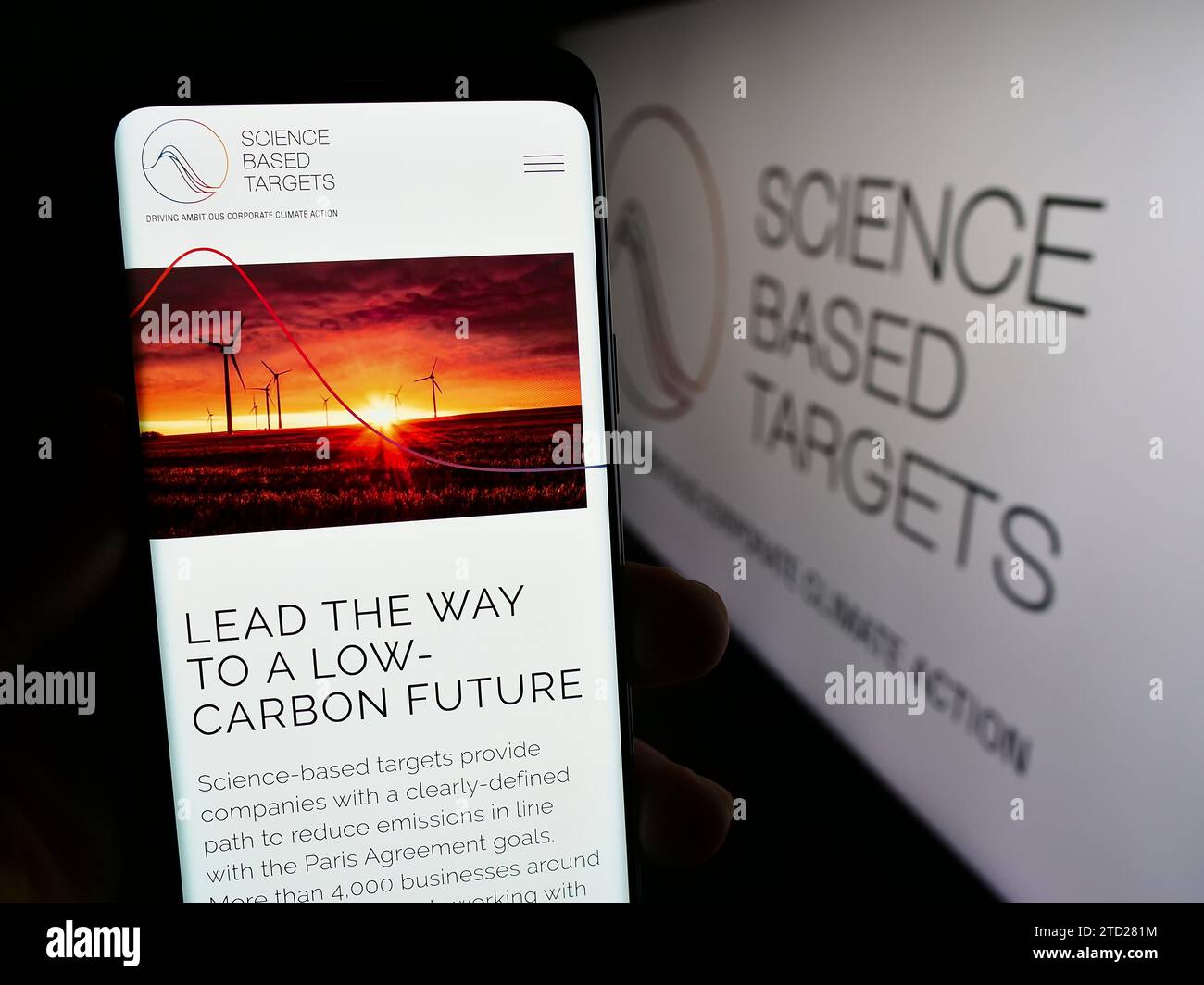 Persona in possesso di smartphone con pagina Web dell'organizzazione Science Based Targets Initiative (SBTi) con logo. Concentrarsi sul centro del display del telefono. Foto Stock