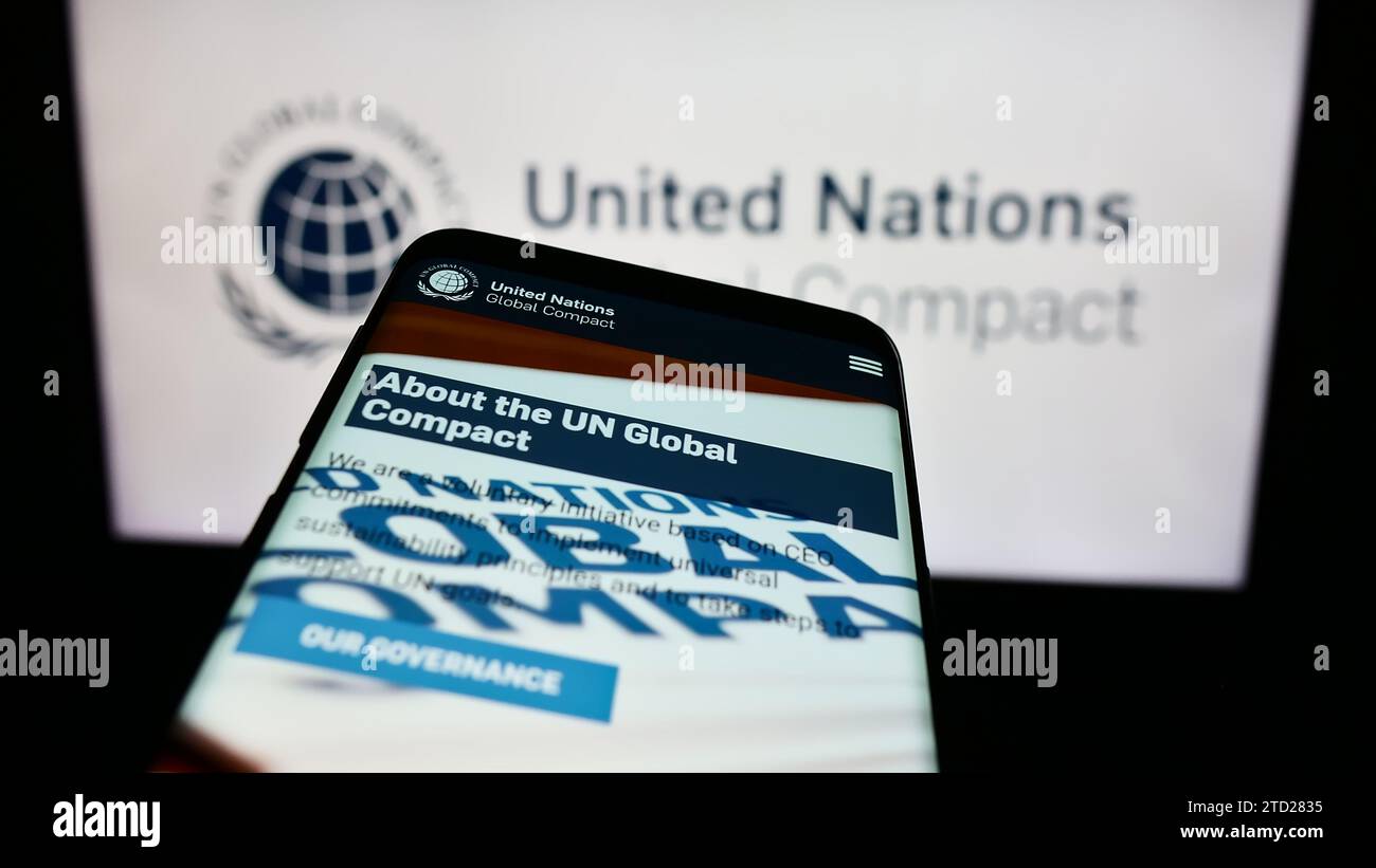 Smartphone con sito Web del Patto delle Nazioni Unite Global Compact davanti al logo. Mettere a fuoco in alto a sinistra sul display del telefono. Foto Stock
