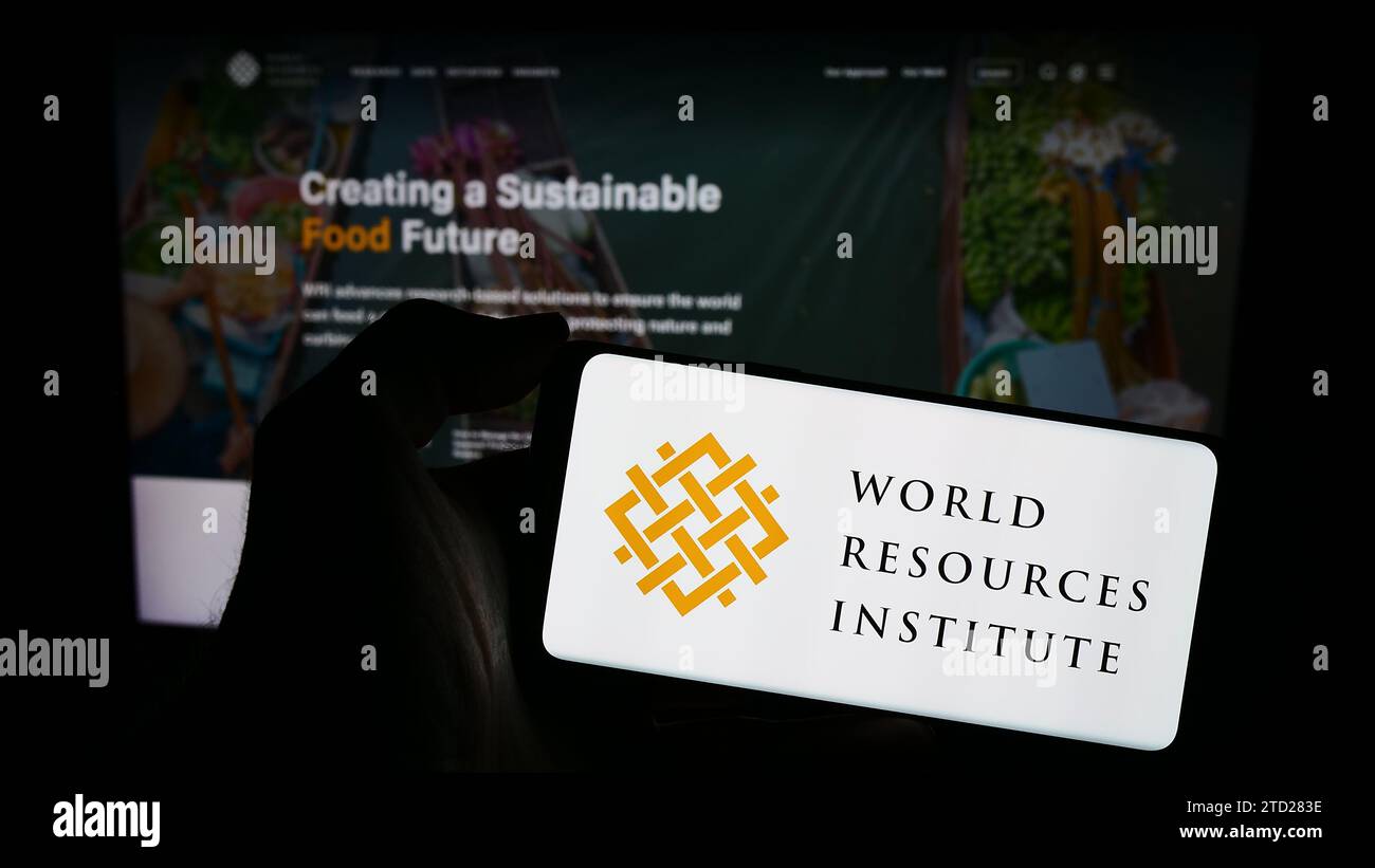 Persona che possiede un telefono cellulare con il logo dell'organizzazione di ricerca World Resources Institute (WRI) davanti alla pagina Web. Concentrarsi sul display del telefono. Foto Stock