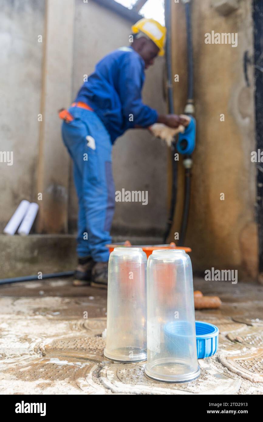 Ritratto verticale di un idraulico africano che pulisce il sistema di filtrazione. Foto Stock