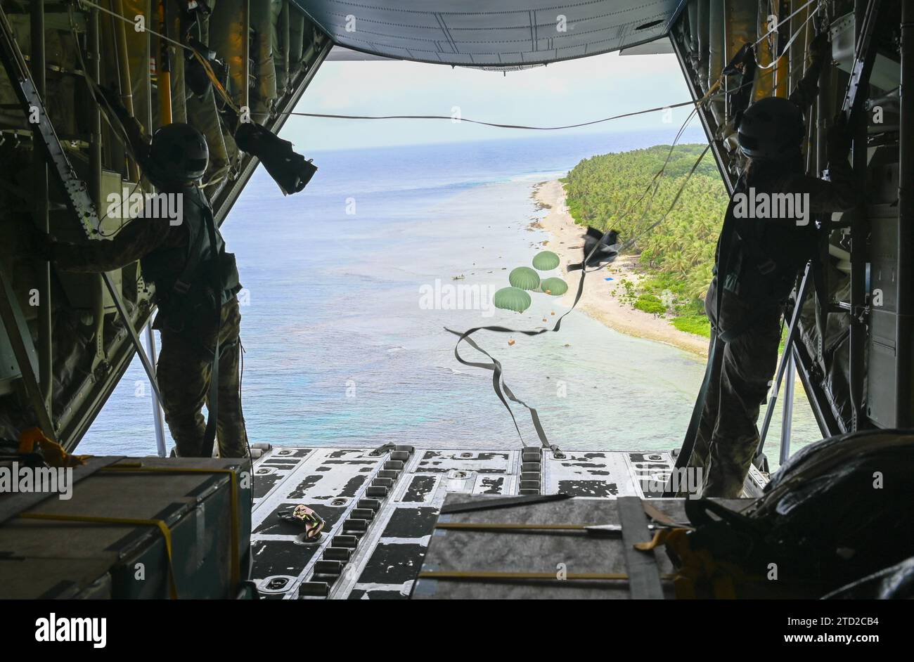 NAMA, Isole Mortlock superiori, Stati Federati di Micronesia. 4 dicembre 2023. I caricatori dell'aeronautica statunitense lanciano pacchetti umanitari in paracadute in una laguna da un aereo C-130J Super Hercules dell'aeronautica militare statunitense, durante l'operazione Christmas Drop, il 4 dicembre 2023 a Nama, Isole Orientali, Micronesia. L'operazione Christmas Drop è la più antica missione umanitaria e di soccorso in caso di catastrofi, che fornisce 71.000 libbre di cibo, regali e provviste per assistere le remote comunità insulari nel Sud del Pacifico. Credito: SRA Allison Martin/US Airforce Photo/Alamy Live News Foto Stock