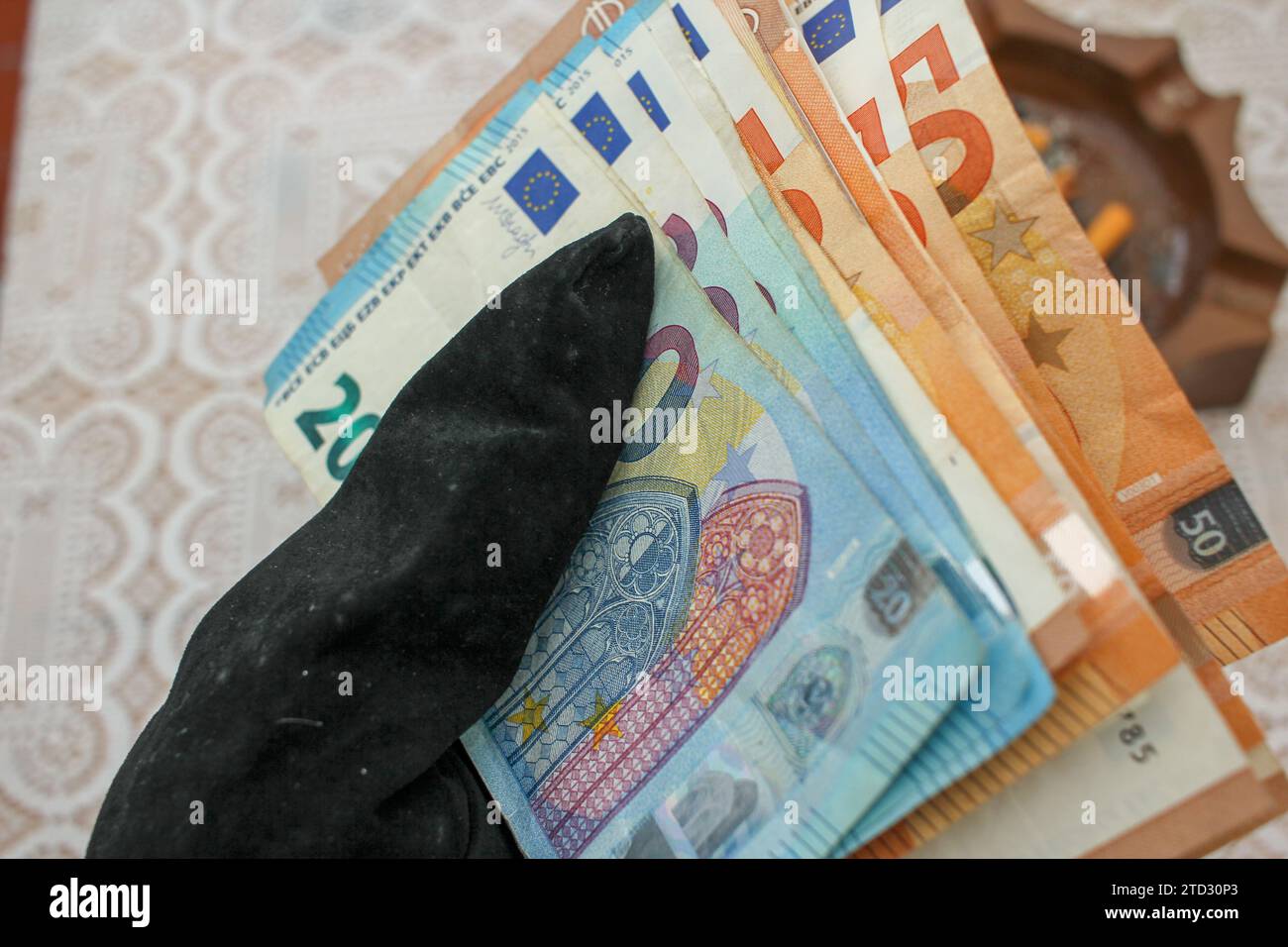 Tocco finanziario: Mano con guanti e bollette in euro Foto Stock