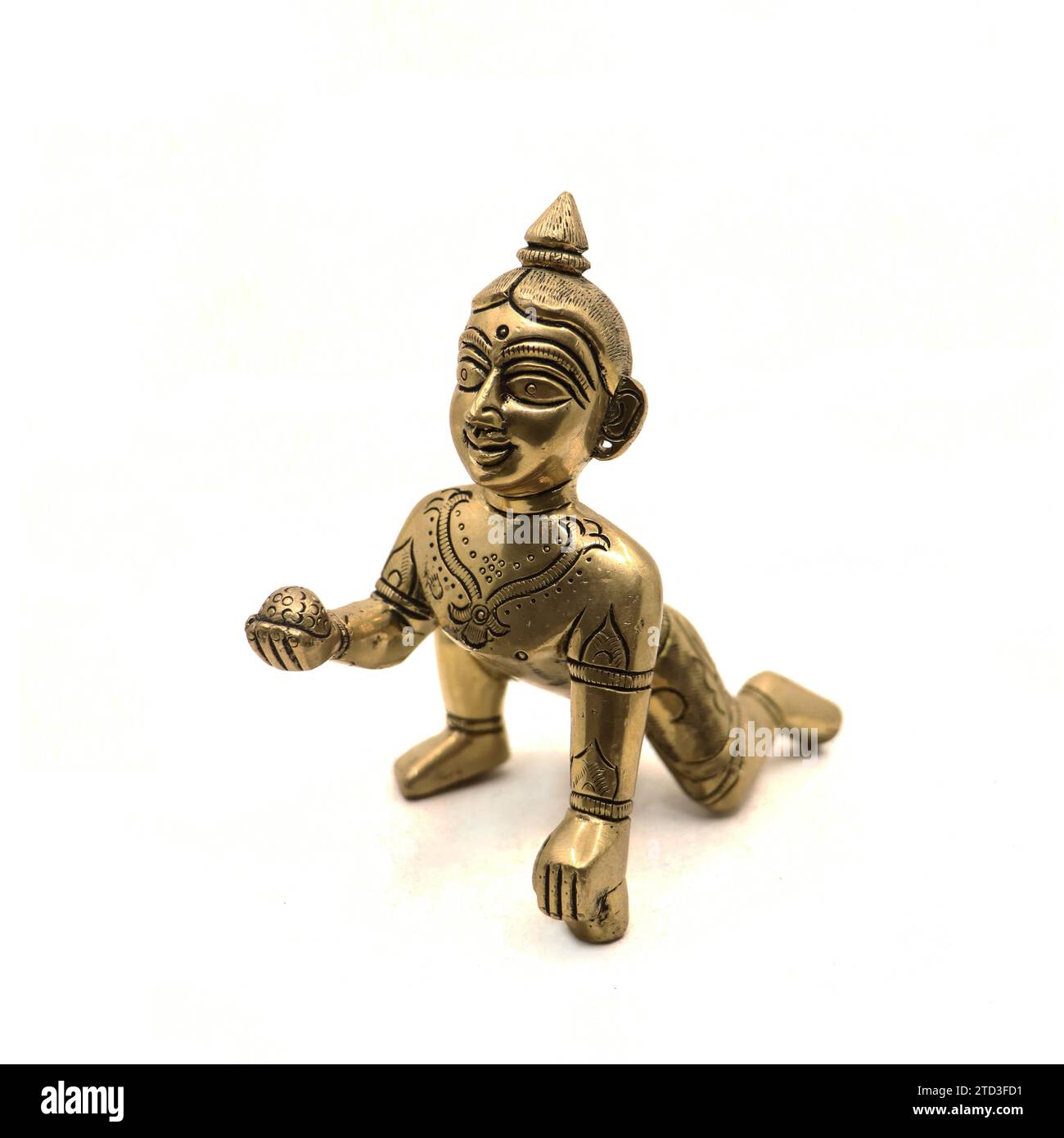 figura dorata d'epoca del piccolo signore krishna chiamato anche gopal con dolce laddu in mano isolato in uno sfondo bianco Foto Stock