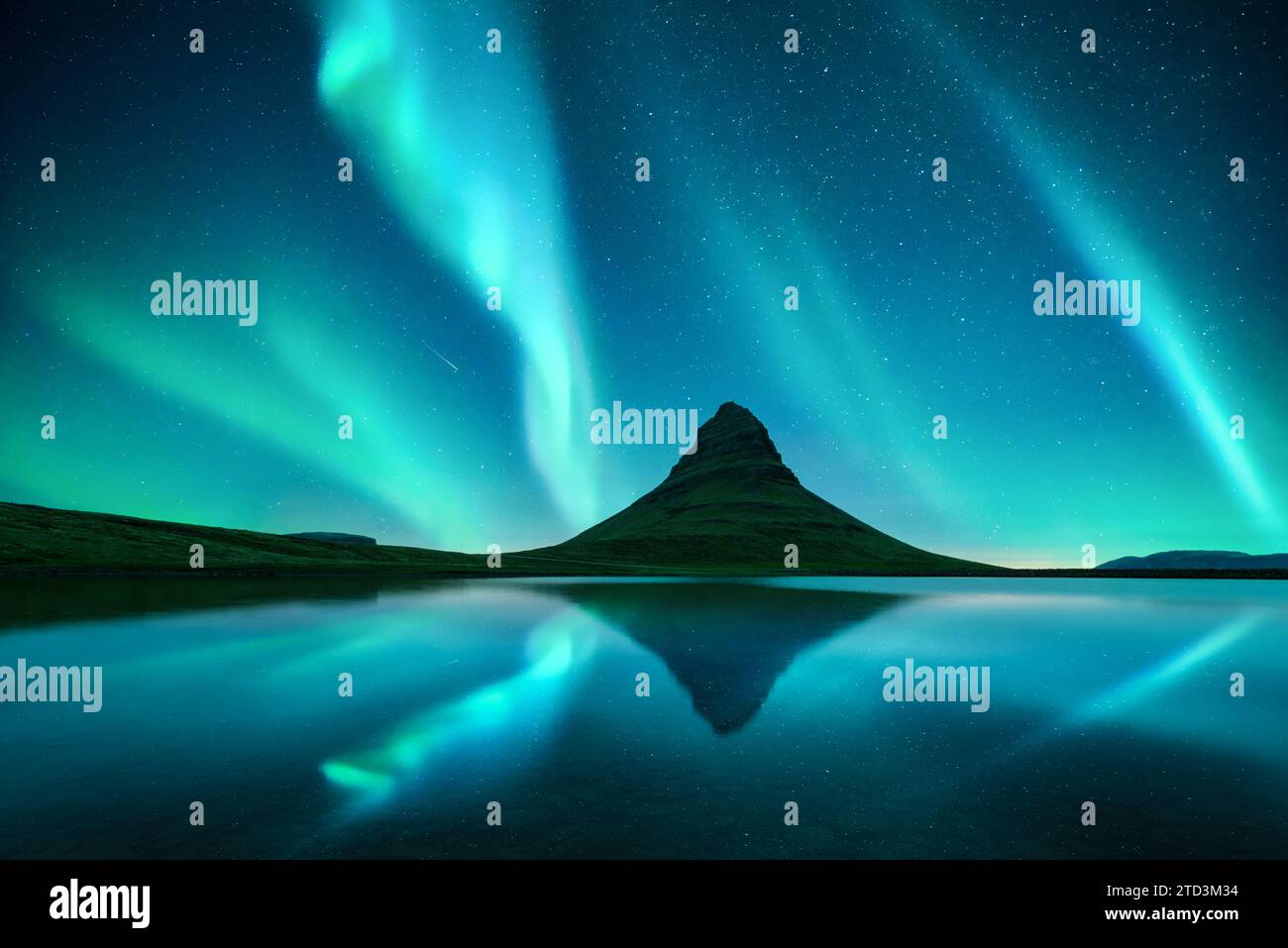 Riflesso della montagna di Kirkjufell e dell'aurora boreale nel cielo stellato nelle acque cristalline del lago vicino alla cascata di Kirkjufellsfoss in Islanda. Incredibile paesaggio notturno con l'aurora boreale Foto Stock