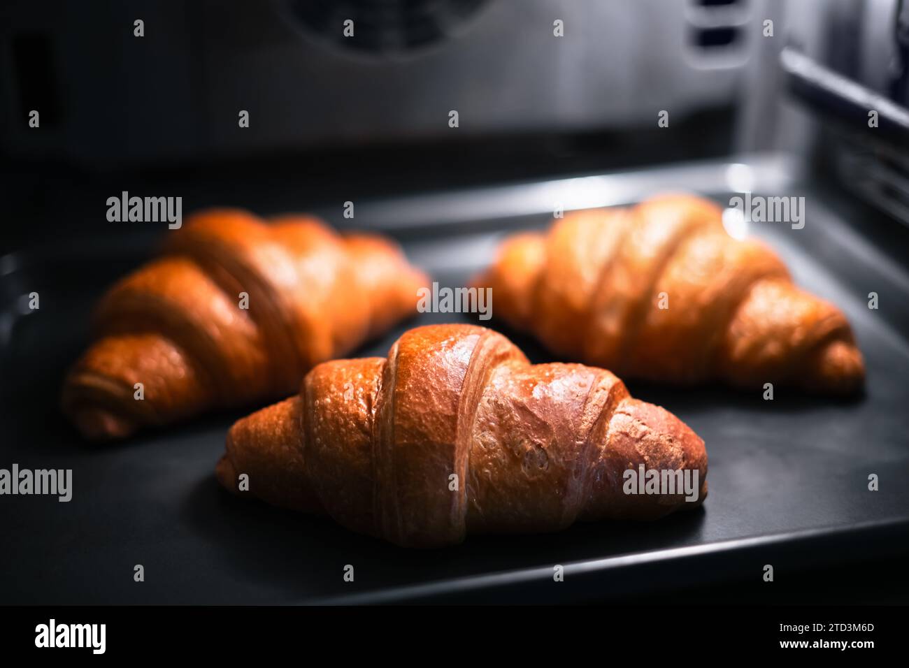 I croissant vengono cotti nel forno domestico. Fotografia del cibo Foto Stock