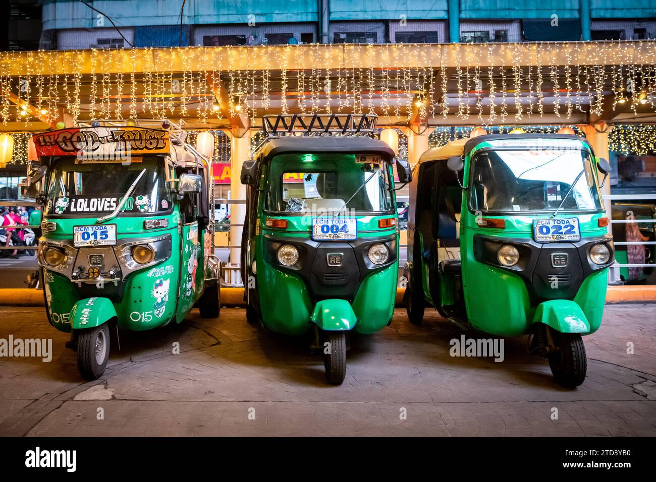 Tre eleganti tuk tuk verdi allineati fuori da un centro commerciale nel quartiere di China Town, ok Manila. Foto Stock