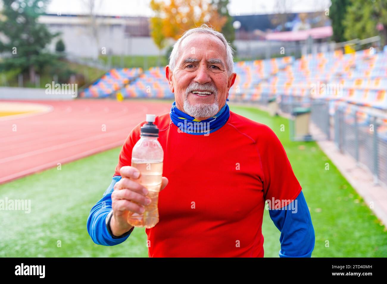 Orgoglioso vecchio con una bottiglia d'acqua riutilizzabile dopo l'allenamento in pista e in campo Foto Stock