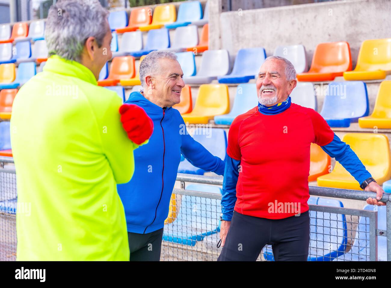 Sorridendo vecchi amici sportivi che si riscaldano in un campo all'aperto prima di iniziare a correre insieme Foto Stock