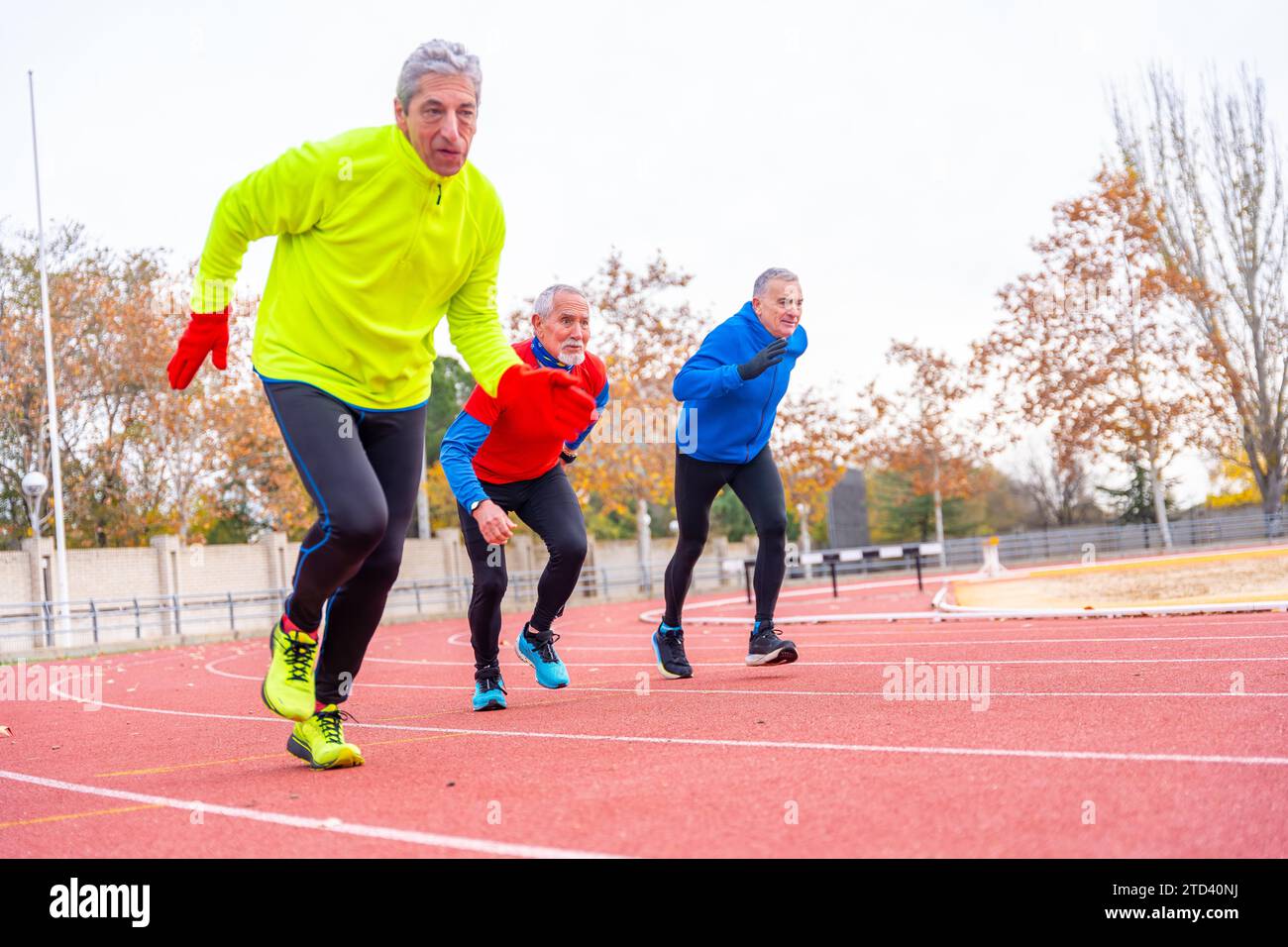 Persone anziane che corrono in una pista sportiva all'aperto in una fredda giornata invernale Foto Stock