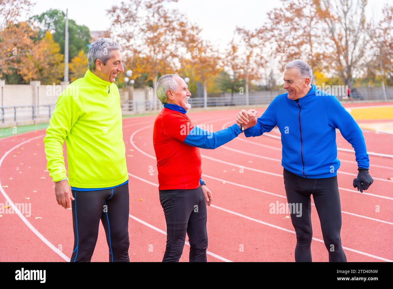 Amici anziani felici che si congratulano per un bel corso di corsa su una pista all'aperto Foto Stock