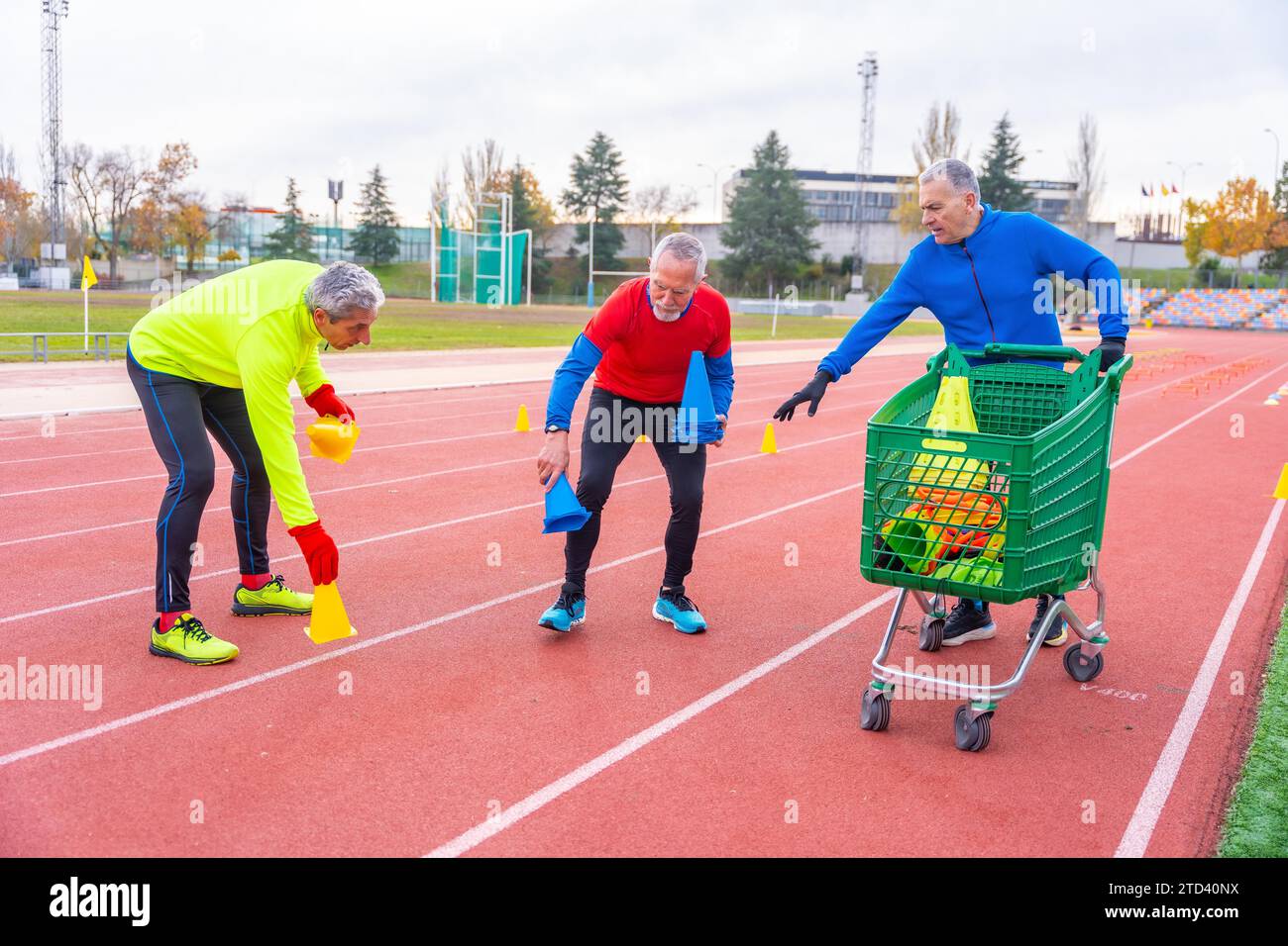 Tre amici sportivi maturi che mettono elementi di allenamento in una pista atletica con Foto Stock