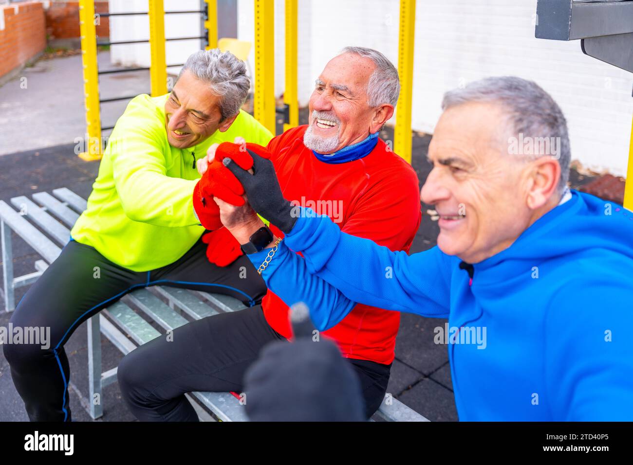 Gli amici sportivi anziani si uniscono alle mani in un campo sportivo all'aperto in inverno Foto Stock
