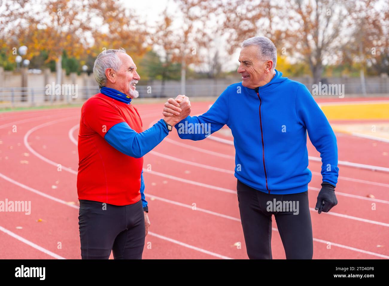 Due anziani in pensione che si tengono per mano con orgoglio dopo aver corso in una pista all'aperto in inverno Foto Stock