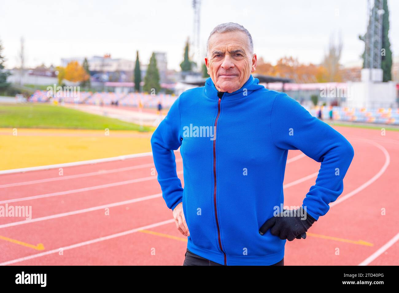Ritratto di un uomo anziano con abiti caldi sportivi in una pista all'aperto Foto Stock
