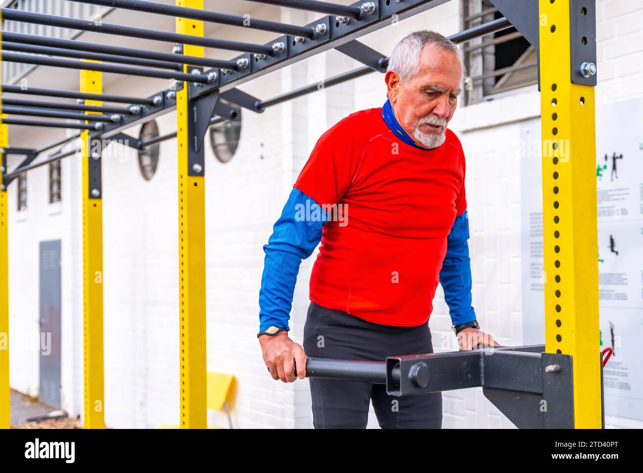 Uomo in pensione maturo con abiti invernali sportivi che si allenano in un campo sportivo pubblico all'aperto Foto Stock