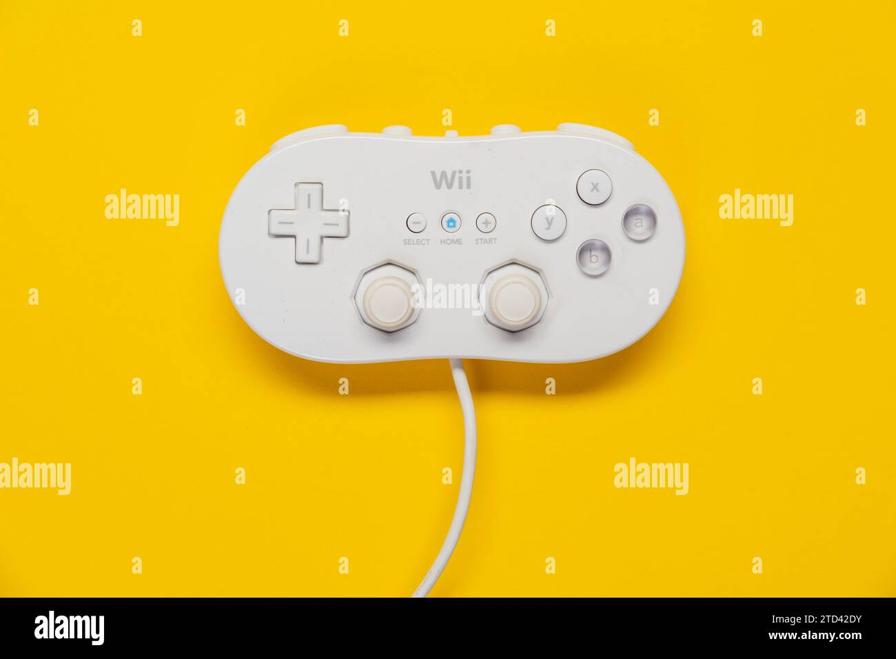 Console di gioco Nintendo Wii con controller di gioco classico di fronte a sfondo giallo, vista dall'alto Foto Stock