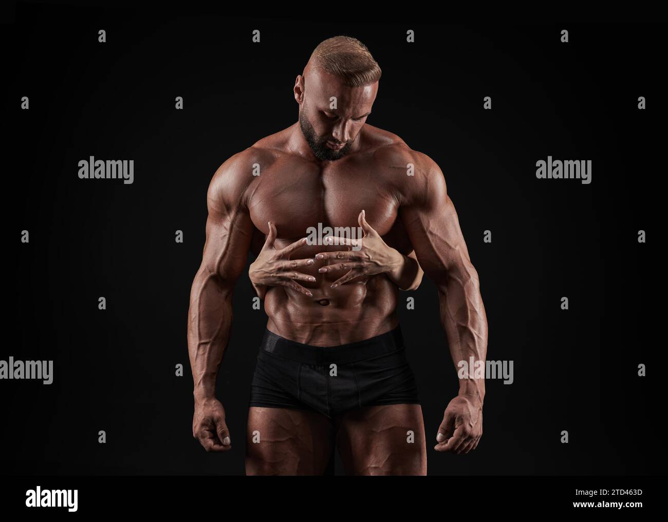 Addome perfetto. Mani femminili che abbracciano e toccano l'uomo muscoloso abs isolato su sfondo nero. Sport, allenamento, bodybuilding. Vista frontale. Foto Stock