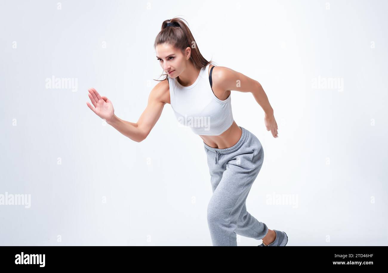 Atleta sportiva su sfondo bianco. Foto di una donna attraente in abbigliamento sportivo alla moda. Movimento dinamico. Vista laterale. Sport e salute Foto Stock