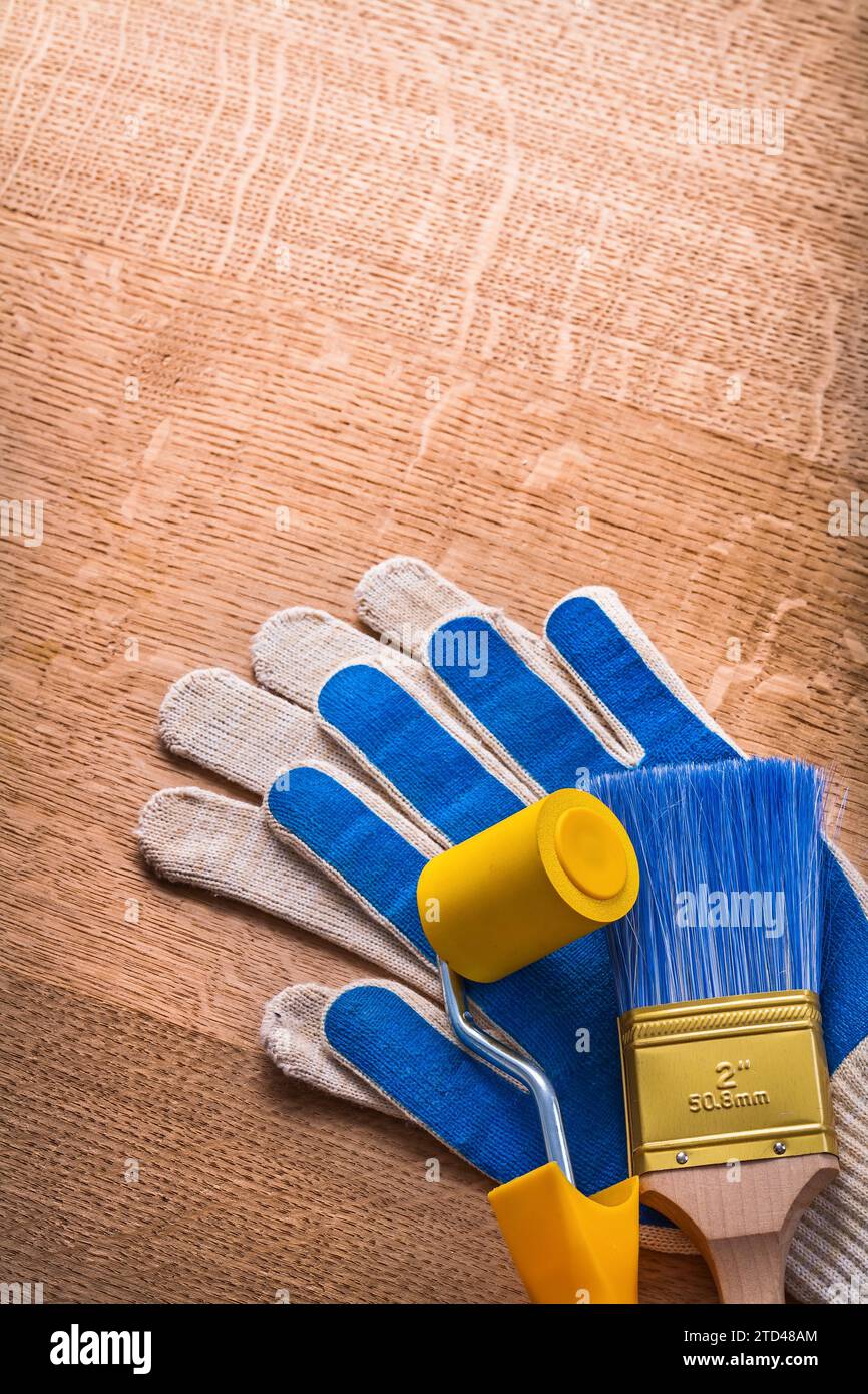 Pennello per verniciatura con guanti protettivi su pannelli in legno concetto di manutenzione Foto Stock