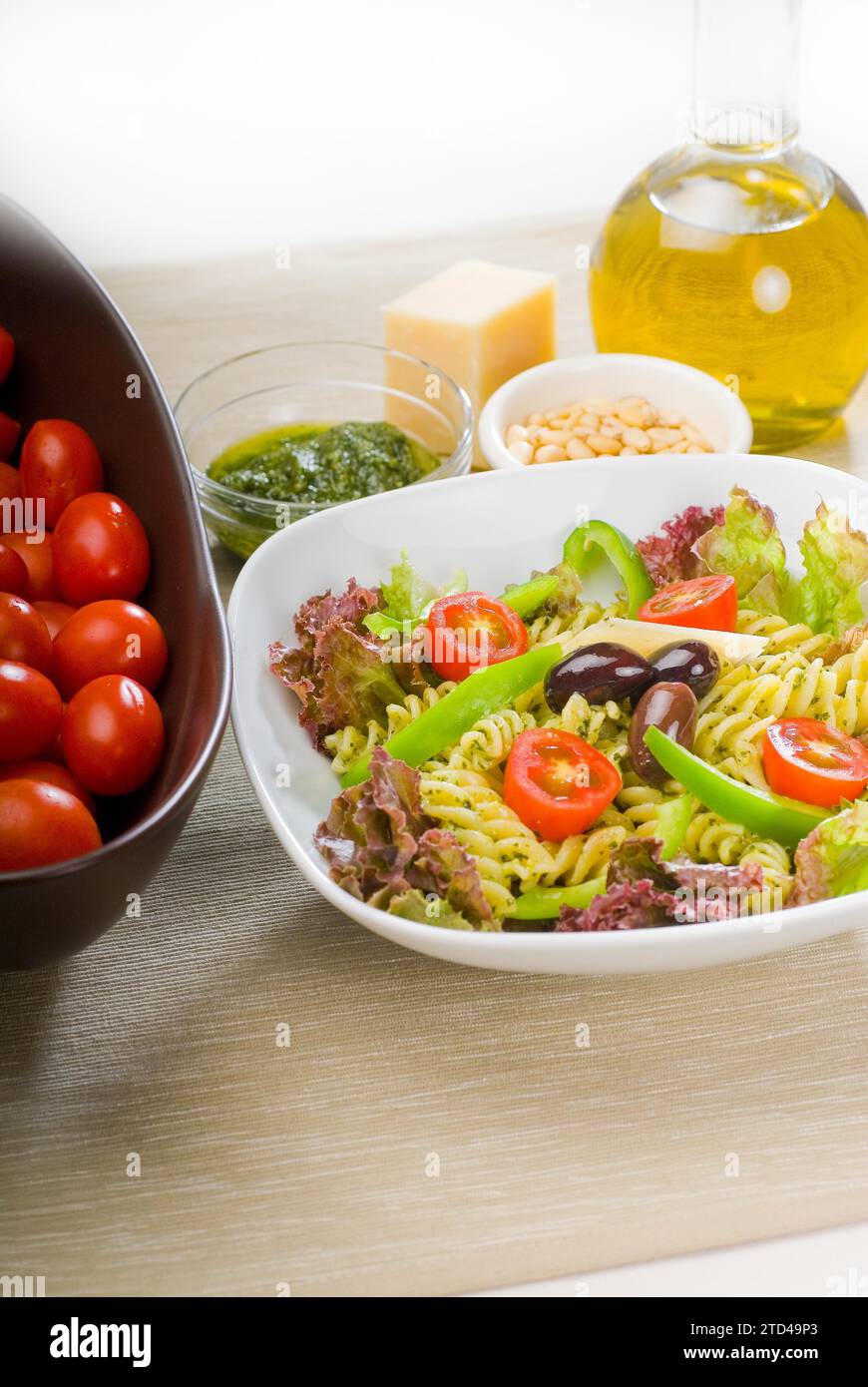 Insalata di pasta fresca e salutare con fusilli italiani fatti in casa con parmigiano, pomodori ciliegini pachino, olive nere e verdure miste, condite con Foto Stock