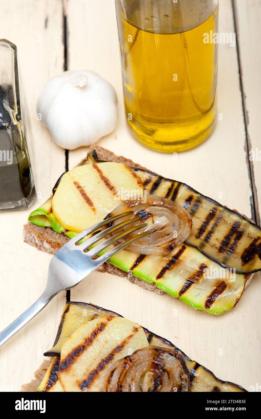 Verdure grigliate su pane rustico su tavola di legno Foto Stock