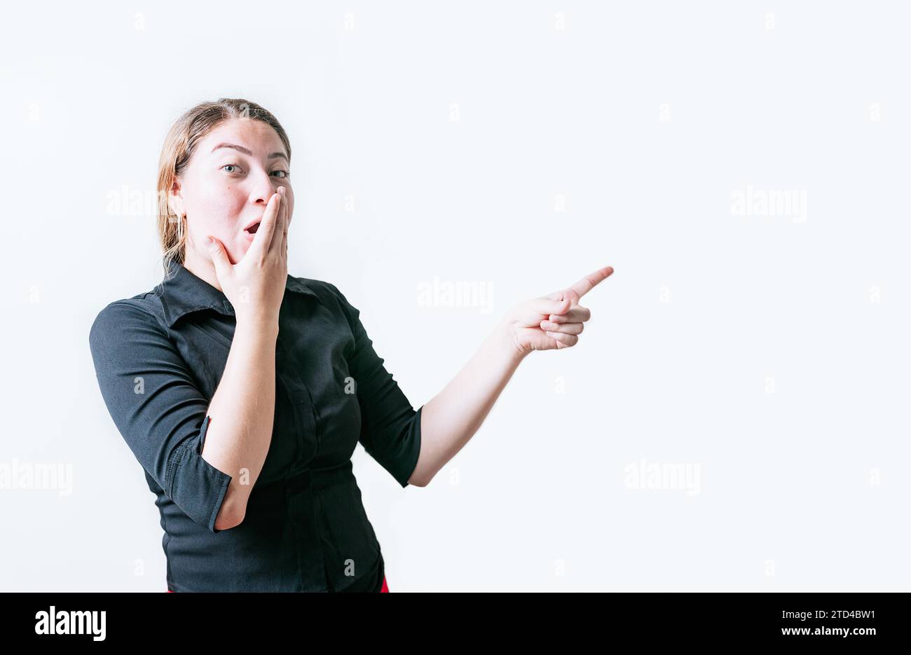 Sorpreso giovane donna che indica una pubblicità isolata. Bella donna che indica uno striscione di lato. Gente divertente che indica una promozione isolata Foto Stock