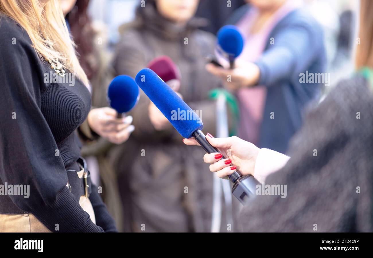Notizie, conferenze stampa o scrum mediatico, reporter donna con microfono, altri giornalisti e operatore di telecamere in background Foto Stock