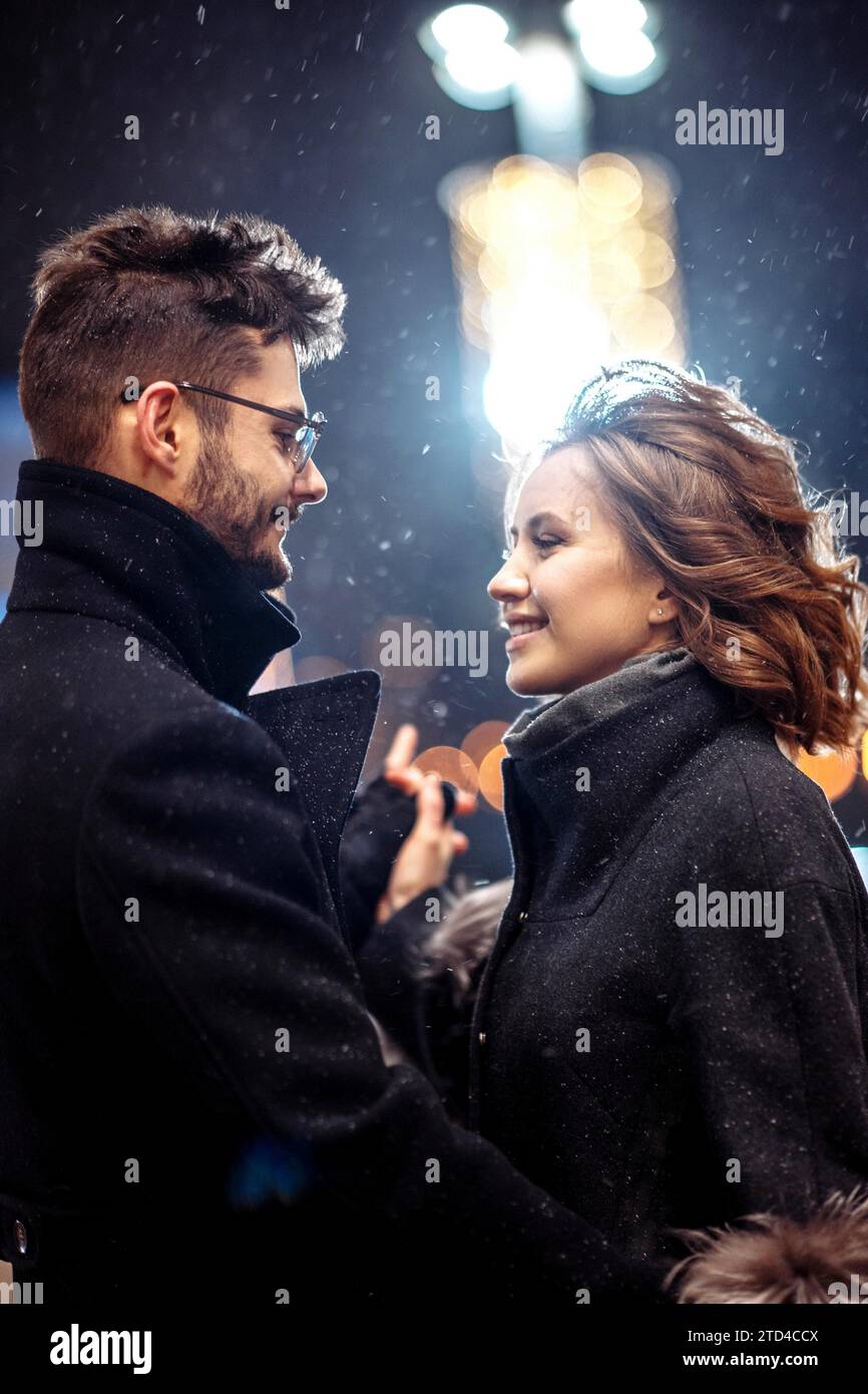 Giovane bella coppia innamorata di ballare in città sotto le nevicate il giorno di san valentino Foto Stock