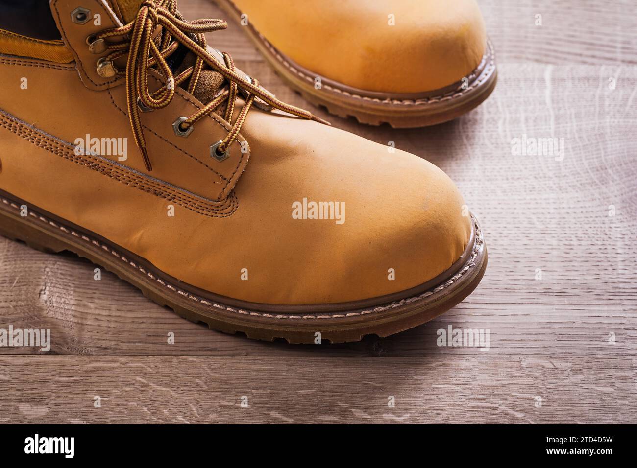 Vista molto ravvicinata di un paio di stivali da lavoro, tavola di legno Foto Stock