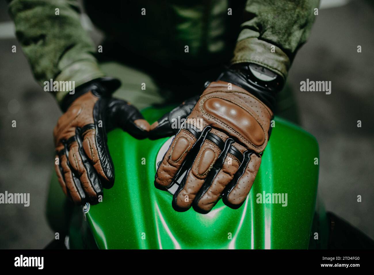 Un motociclista mostra i suoi guanti in pelle marrone per un viaggio alla macchina fotografica, l'attrezzatura Moto Foto Stock
